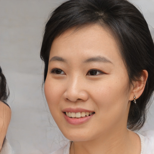 Joyful asian young-adult female with medium  brown hair and brown eyes