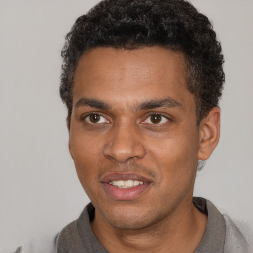 Joyful black young-adult male with short  black hair and brown eyes