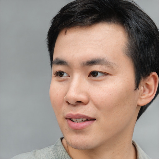 Joyful asian young-adult male with short  black hair and brown eyes