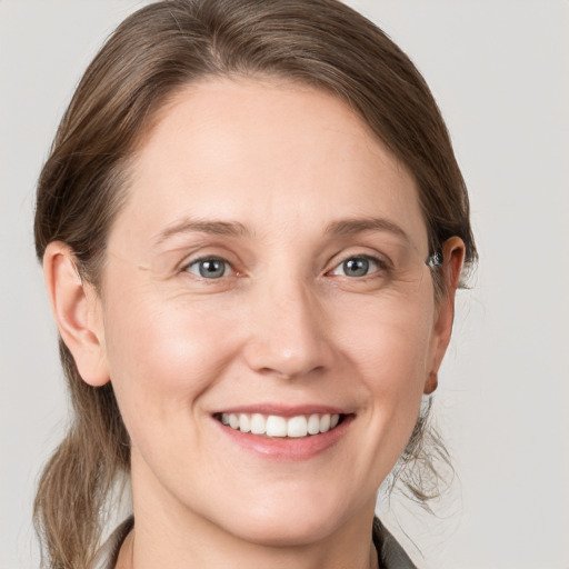 Joyful white young-adult female with medium  brown hair and grey eyes