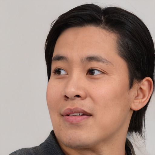 Joyful asian young-adult male with medium  black hair and brown eyes