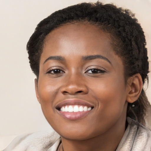 Joyful black young-adult female with short  brown hair and brown eyes