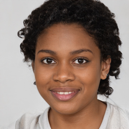 Joyful black young-adult female with long  black hair and brown eyes