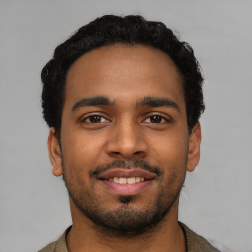 Joyful black young-adult male with short  black hair and brown eyes