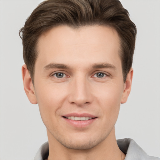 Joyful white young-adult male with short  brown hair and grey eyes