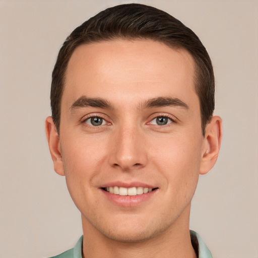 Joyful white young-adult male with short  brown hair and grey eyes