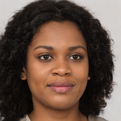 Joyful black young-adult female with long  brown hair and brown eyes