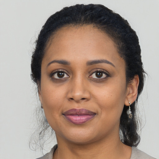 Joyful black young-adult female with long  black hair and brown eyes