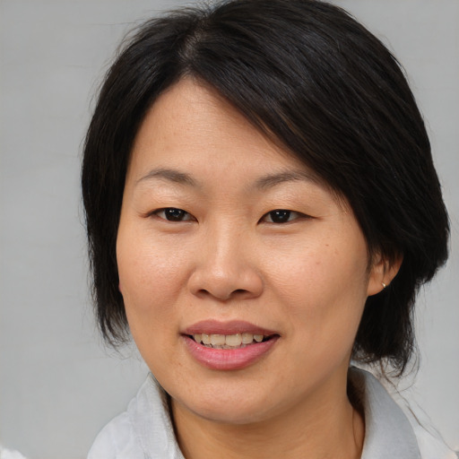 Joyful asian adult female with medium  brown hair and brown eyes