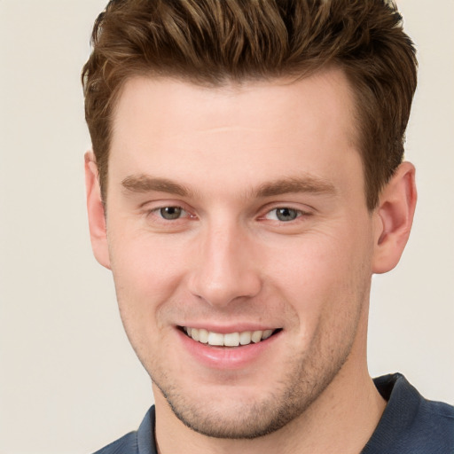 Joyful white young-adult male with short  brown hair and grey eyes