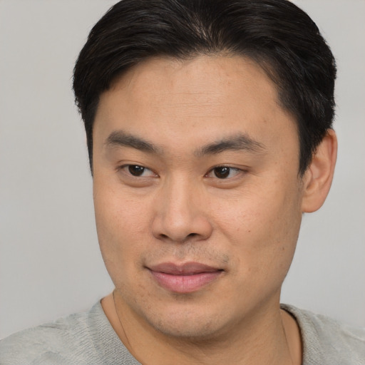 Joyful asian young-adult male with short  brown hair and brown eyes