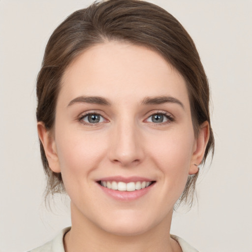 Joyful white young-adult female with medium  brown hair and grey eyes