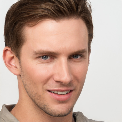 Joyful white young-adult male with short  brown hair and grey eyes