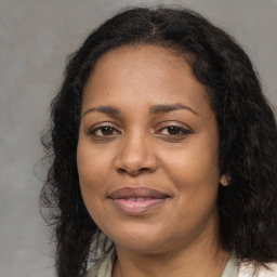 Joyful black young-adult female with long  brown hair and brown eyes