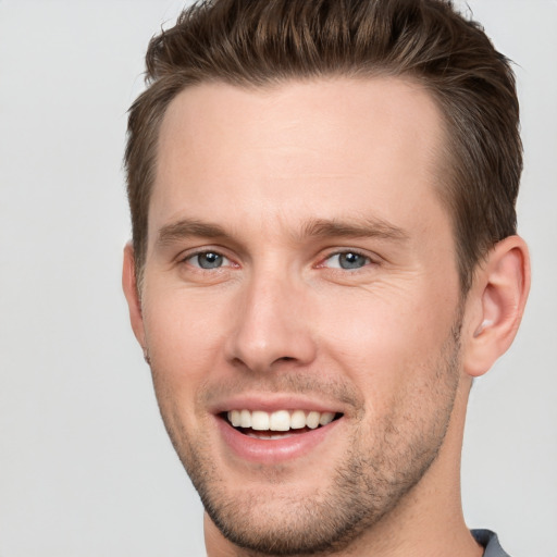 Joyful white young-adult male with short  brown hair and grey eyes