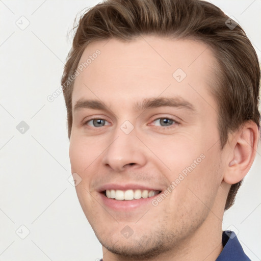 Joyful white young-adult male with short  brown hair and grey eyes