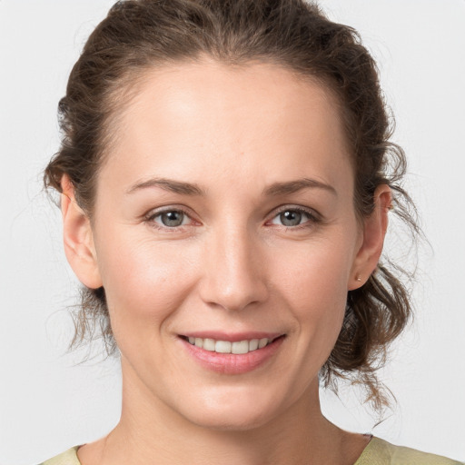 Joyful white young-adult female with medium  brown hair and grey eyes