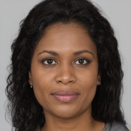 Joyful black young-adult female with long  brown hair and brown eyes