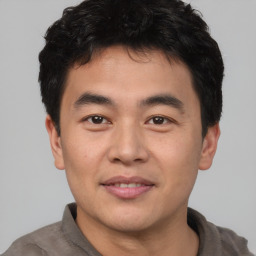 Joyful asian young-adult male with short  brown hair and brown eyes