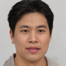 Joyful asian young-adult male with short  brown hair and brown eyes