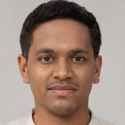 Joyful black young-adult male with short  brown hair and brown eyes