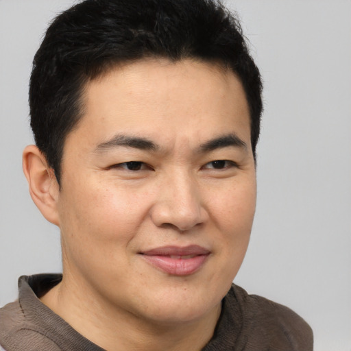 Joyful asian adult male with short  brown hair and brown eyes