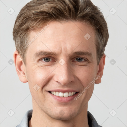 Joyful white young-adult male with short  brown hair and grey eyes