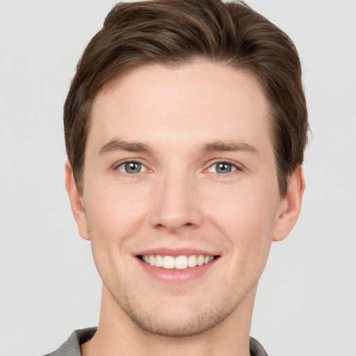 Joyful white young-adult male with short  brown hair and grey eyes