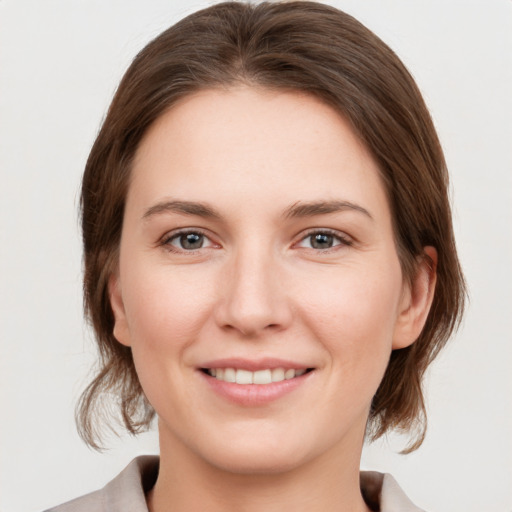 Joyful white young-adult female with medium  brown hair and grey eyes