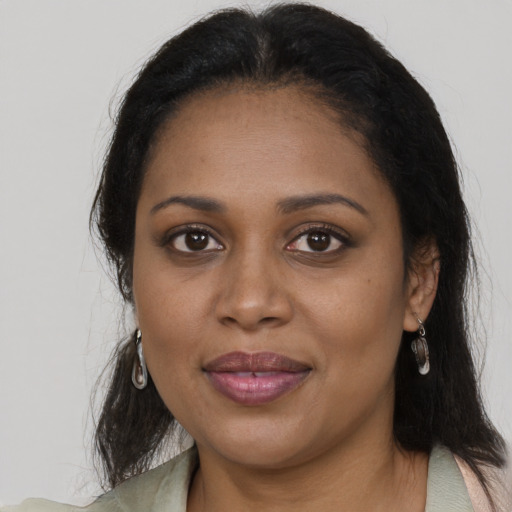 Joyful black adult female with long  brown hair and brown eyes