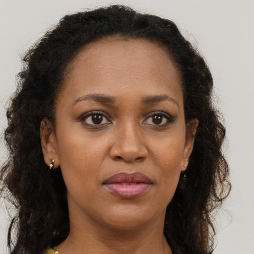 Joyful black young-adult female with long  brown hair and brown eyes