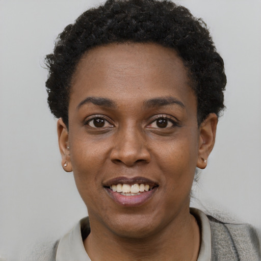 Joyful black young-adult female with short  black hair and brown eyes