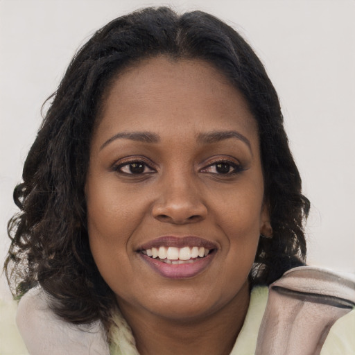 Joyful black young-adult female with long  brown hair and brown eyes