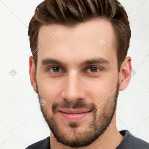 Joyful white young-adult male with short  brown hair and grey eyes