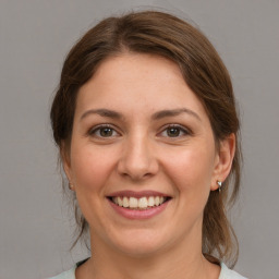 Joyful white young-adult female with medium  brown hair and grey eyes