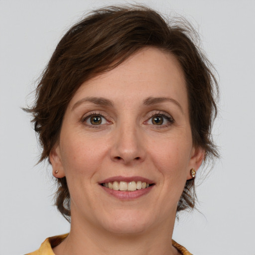 Joyful white young-adult female with medium  brown hair and green eyes