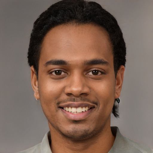 Joyful black young-adult male with short  black hair and brown eyes