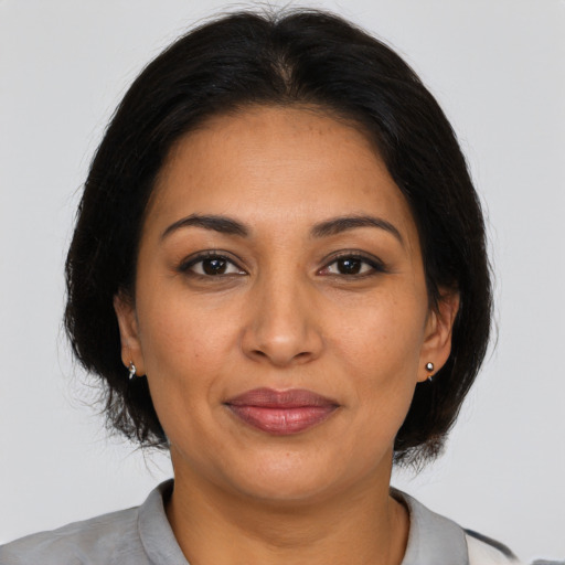 Joyful latino adult female with medium  brown hair and brown eyes