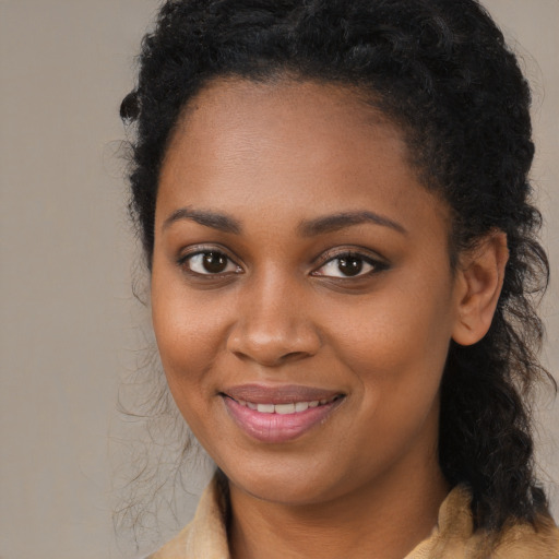 Joyful black young-adult female with long  black hair and brown eyes