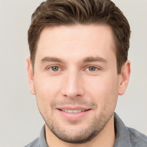 Joyful white young-adult male with short  brown hair and grey eyes