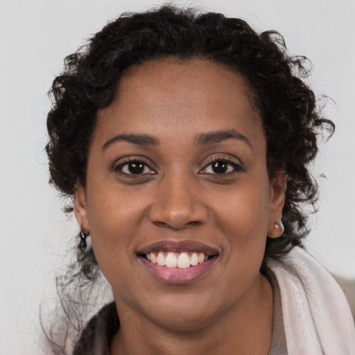 Joyful black young-adult female with long  brown hair and brown eyes