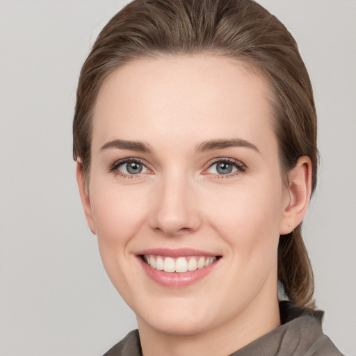 Joyful white young-adult female with medium  brown hair and grey eyes