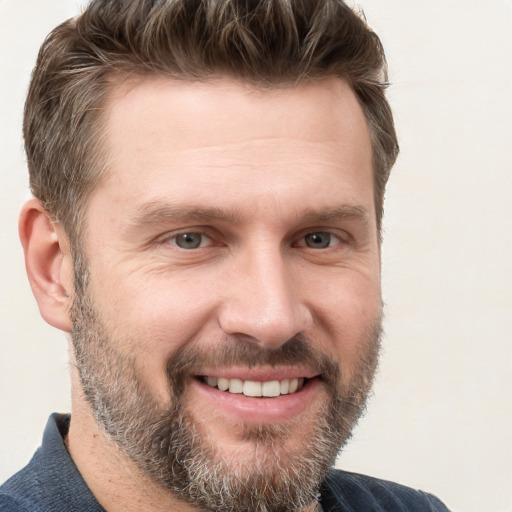 Joyful white adult male with short  brown hair and grey eyes