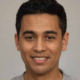 Joyful latino young-adult male with short  black hair and brown eyes