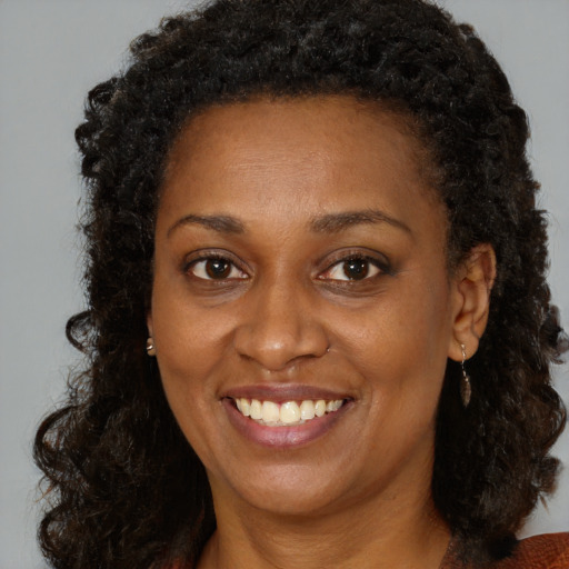 Joyful black young-adult female with long  brown hair and brown eyes