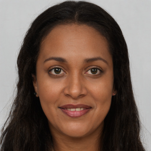 Joyful black young-adult female with long  brown hair and brown eyes