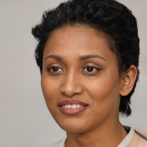 Joyful black young-adult female with short  black hair and brown eyes