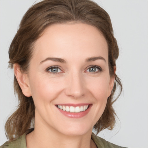 Joyful white young-adult female with medium  brown hair and grey eyes