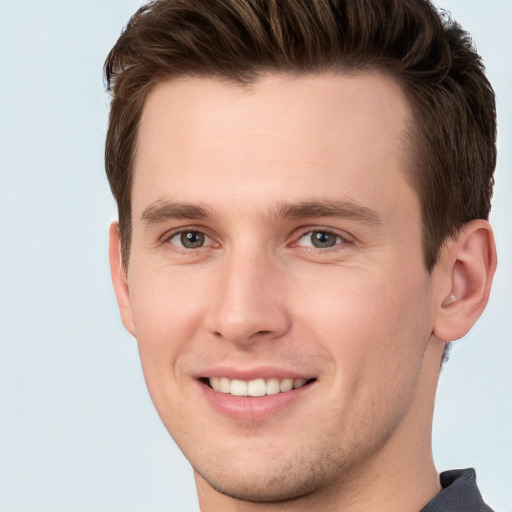 Joyful white young-adult male with short  brown hair and grey eyes