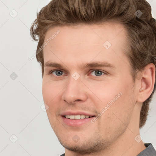 Joyful white young-adult male with short  brown hair and grey eyes